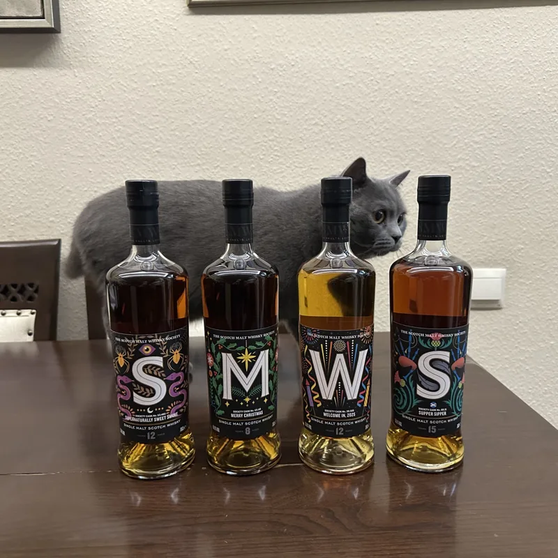 Pablo the cat peeking out from behind four SMWS bottles